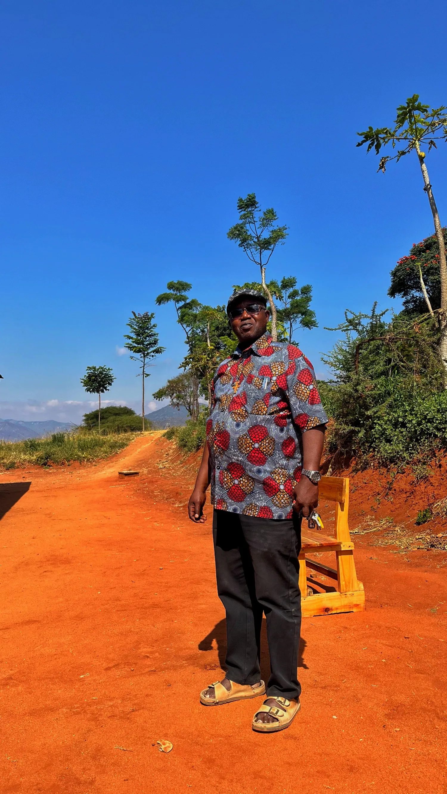 Fr. Gaudence Aikaruwa Shayo, OFM Cap, standing on the red dirt road at Mlali